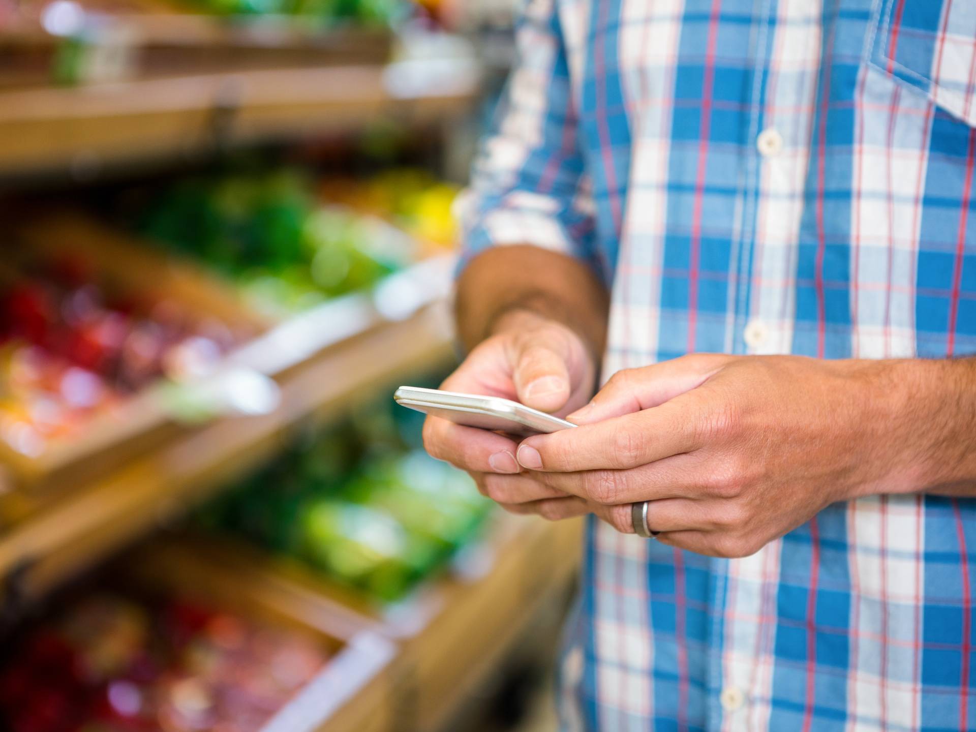 man shopping at grocery with phone